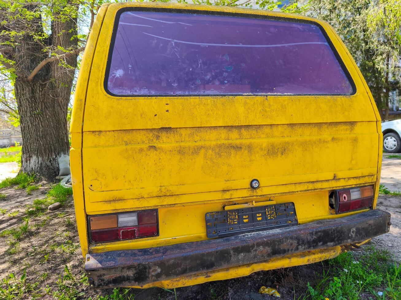 Yellow van with red window and license plate. The van is parked in a grassy area. photo