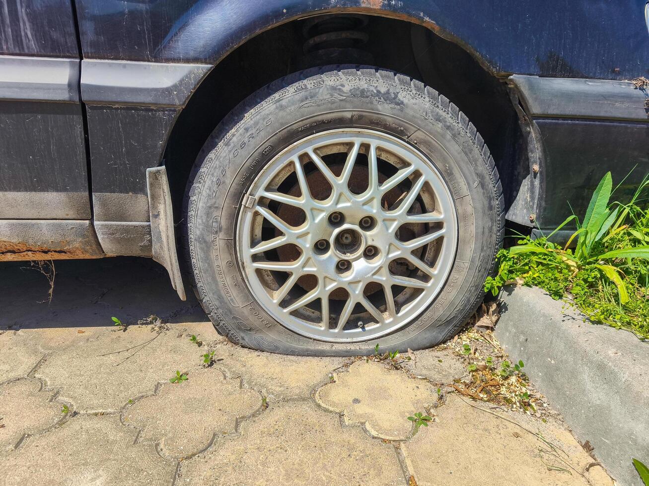 A car tire is flat and has a hole in it. The tire is on a cement surface photo