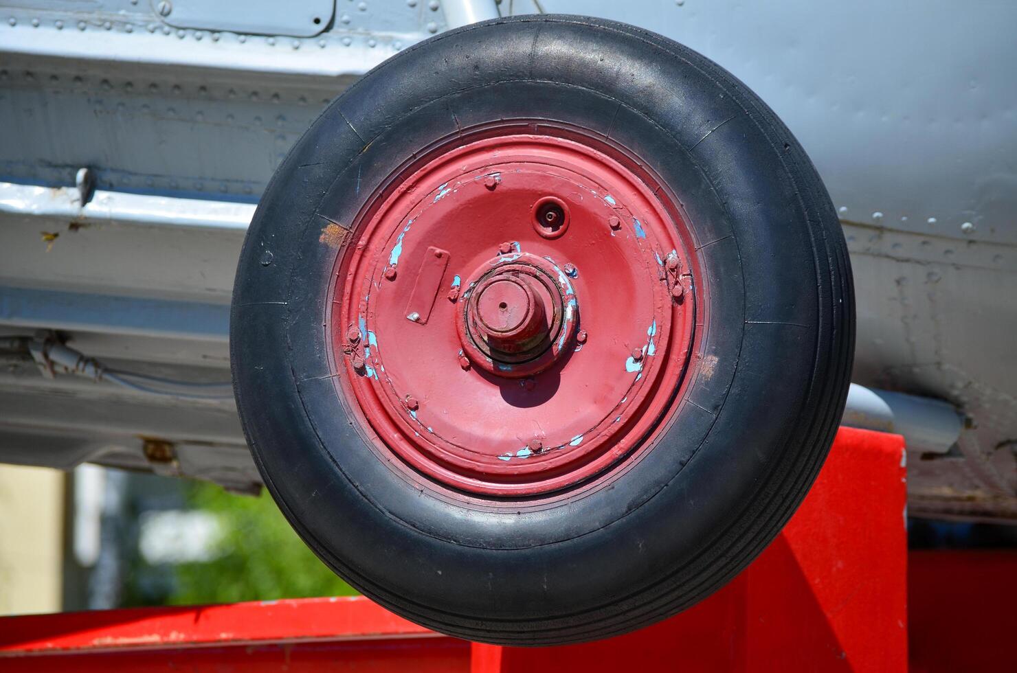 A red tire with black rubber is on a red platform. The tire is old and worn, and it is from a military aircraft. Concept of nostalgia and history photo