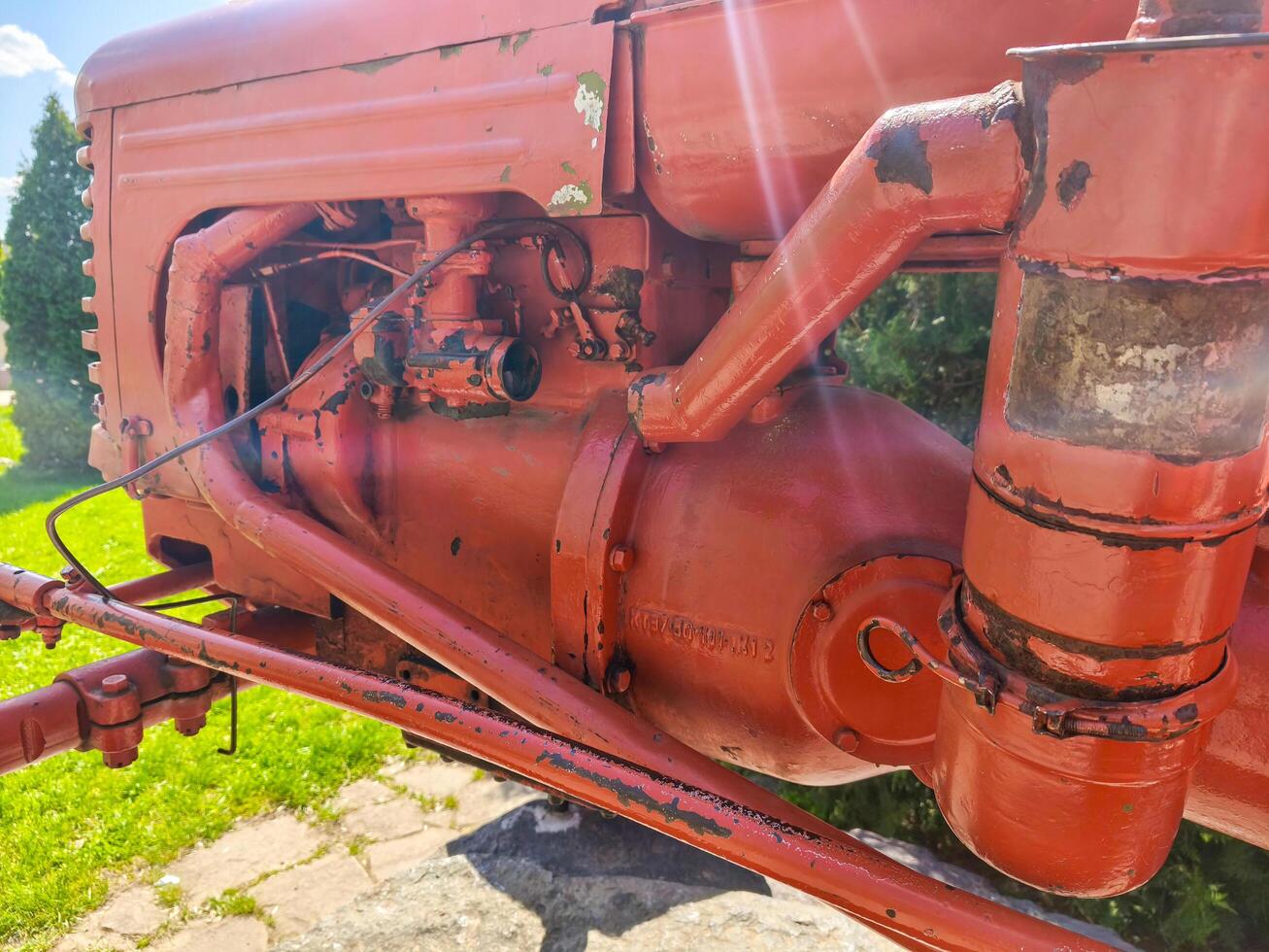 A red tractor with a black engine. The engine is old and rusty. The tractor is parked in a grassy area photo