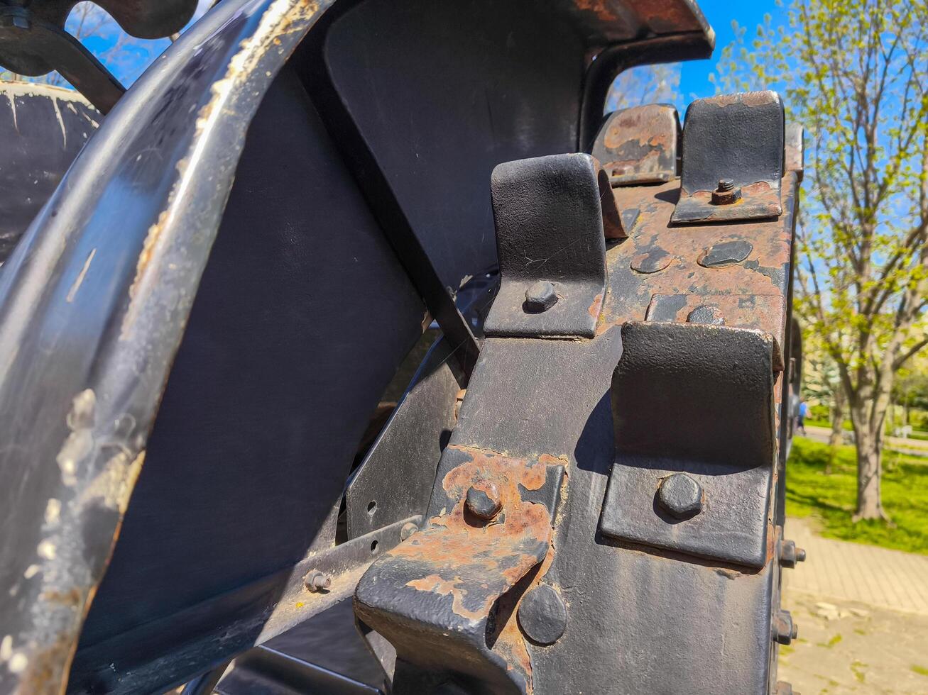 The back of a tractor with rusted metal parts. The rusted parts are black and the tractor is black photo