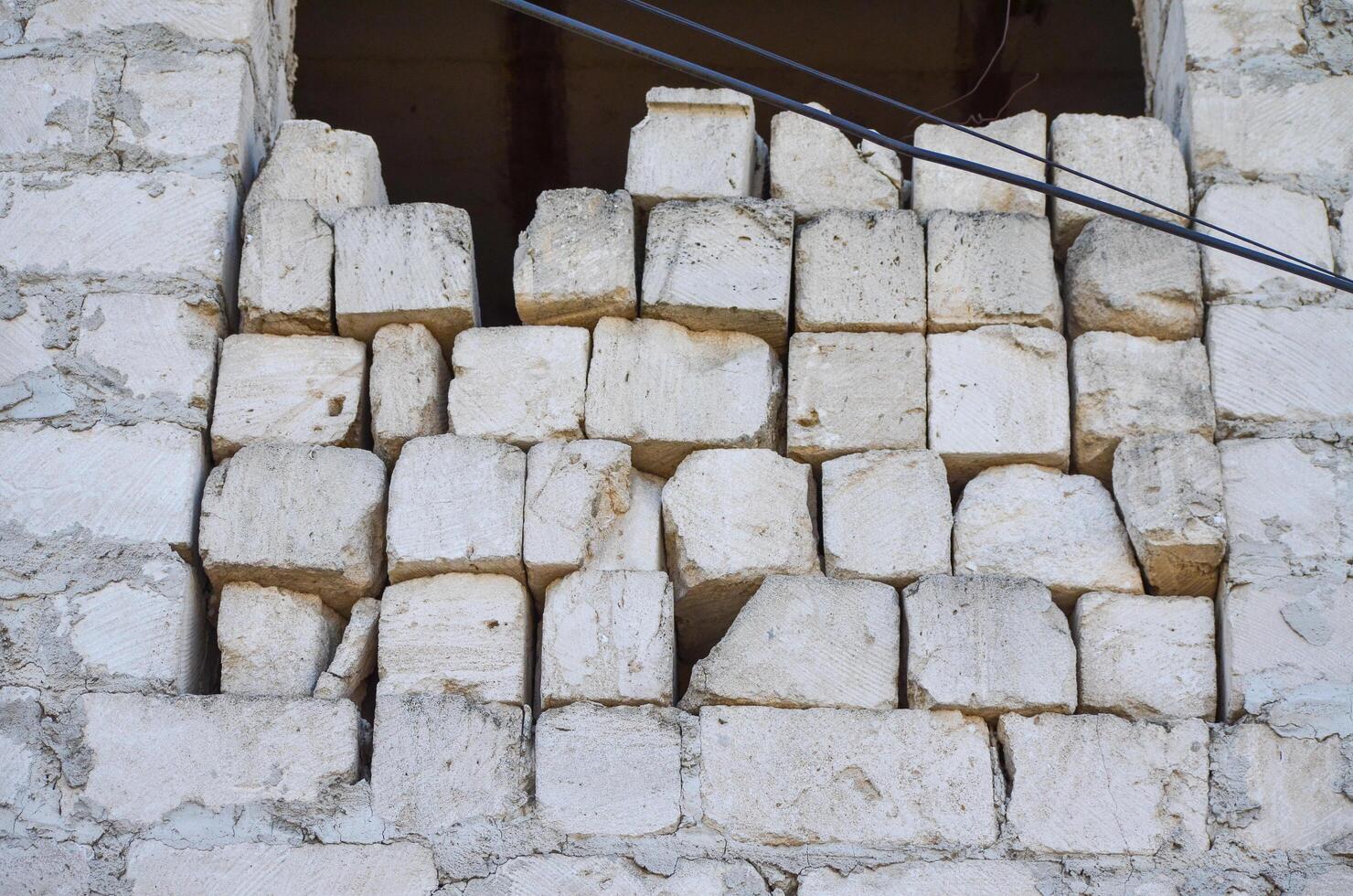 A wall made of white bricks with a hole in it. The bricks are stacked in a way that they are not in a straight line photo