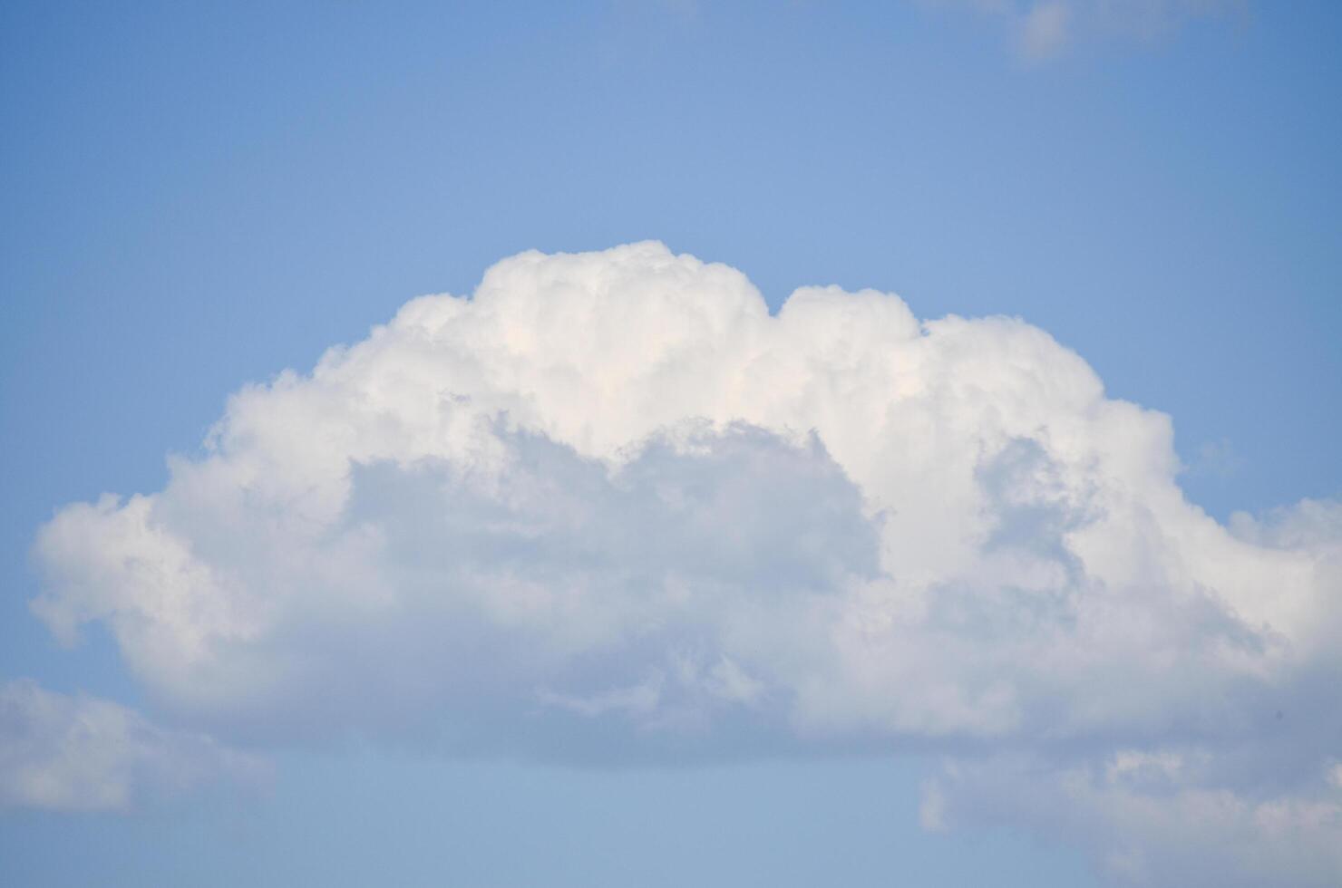 A large cloud in the sky with a blue sky background. The cloud is white and fluffy. The sky is clear and bright, with no signs of rain or storm. Concept of calm and tranquility photo
