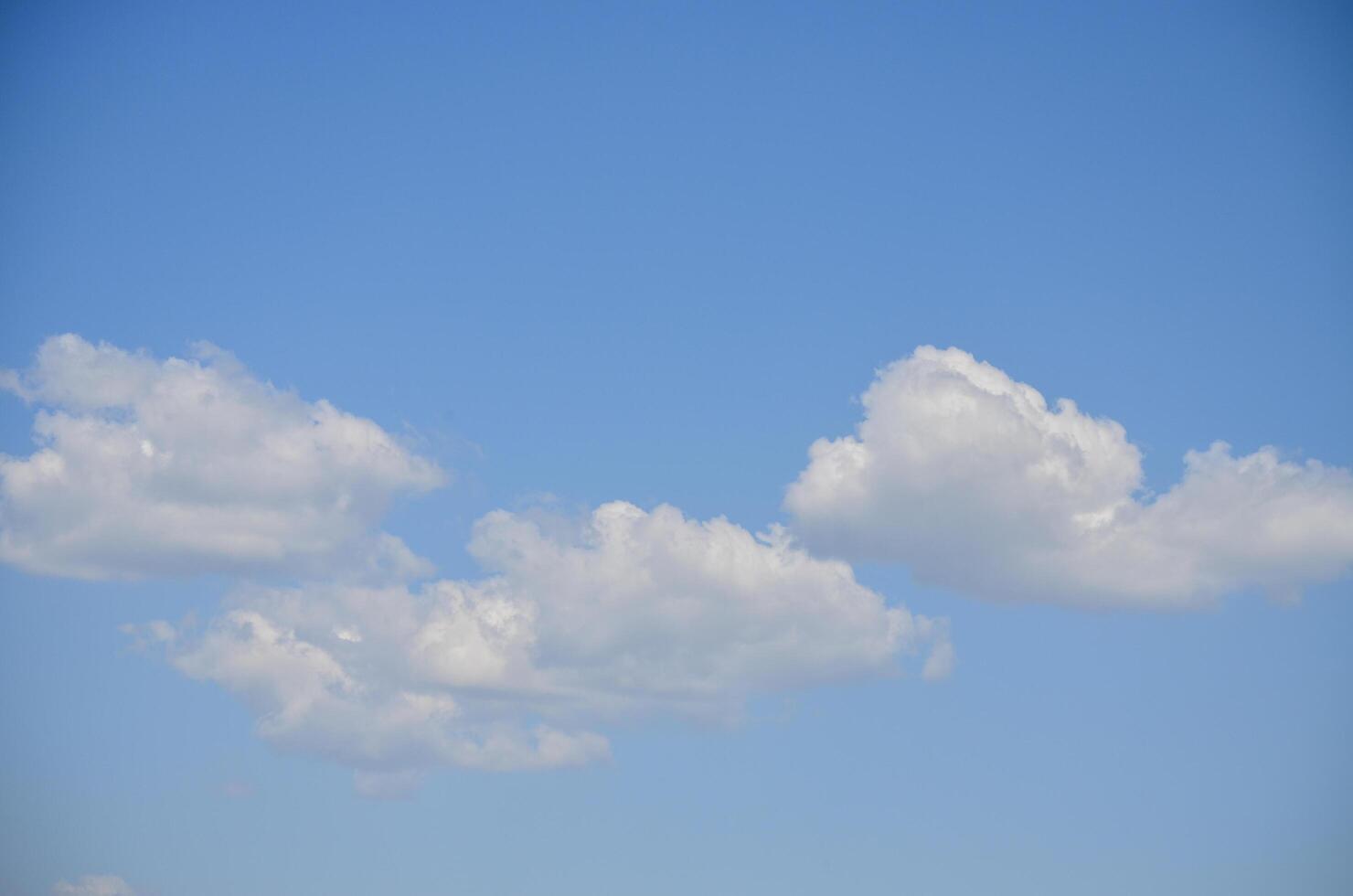 The sky is blue and clear with a few clouds scattered throughout. The clouds are small and fluffy, giving the sky a light and airy feel. Scene is calm and peaceful, with the blue sky photo