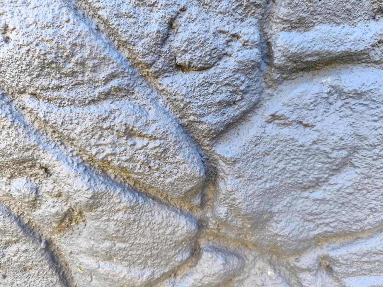 The image is of a wall with a grey and white texture. The wall appears to be made of stone or concrete, and it has a rough, uneven surface. The wall is not painted, and it has a natural photo
