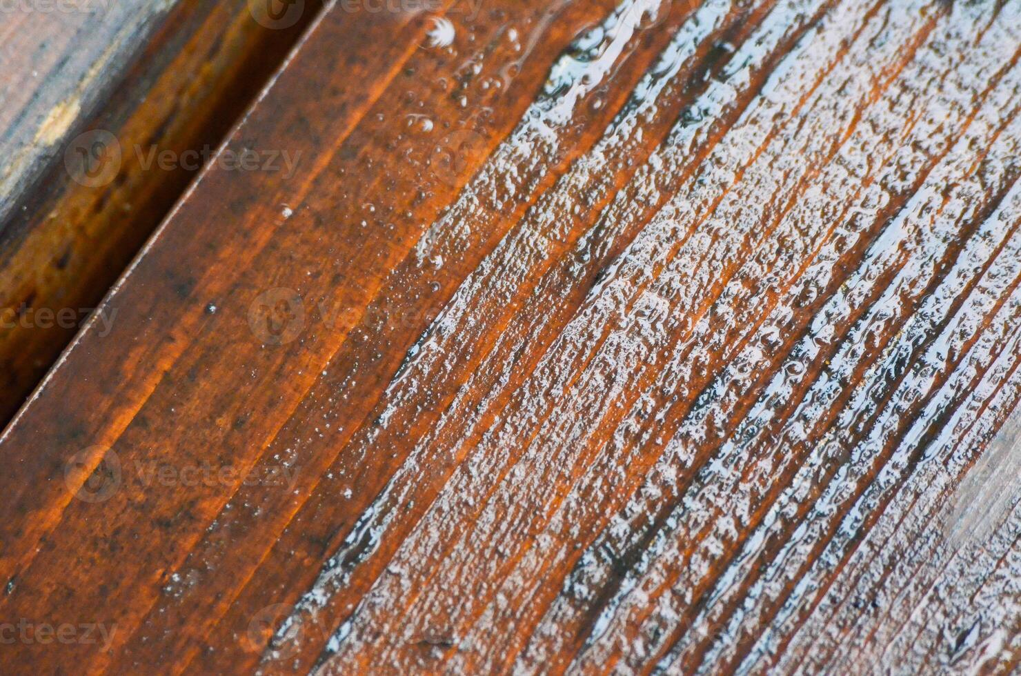The wooden surface has a distinct grain pattern that is clearly visible. The wood appears to be wet, possibly due to rain or humidity. The combination of the wood grain photo