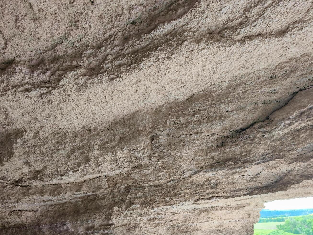 A rocky surface with a lot of cracks and crevices. The surface appears to be made of stone and has a rough texture. The cracks and crevices give the impression of a rugged and uneven terrain photo