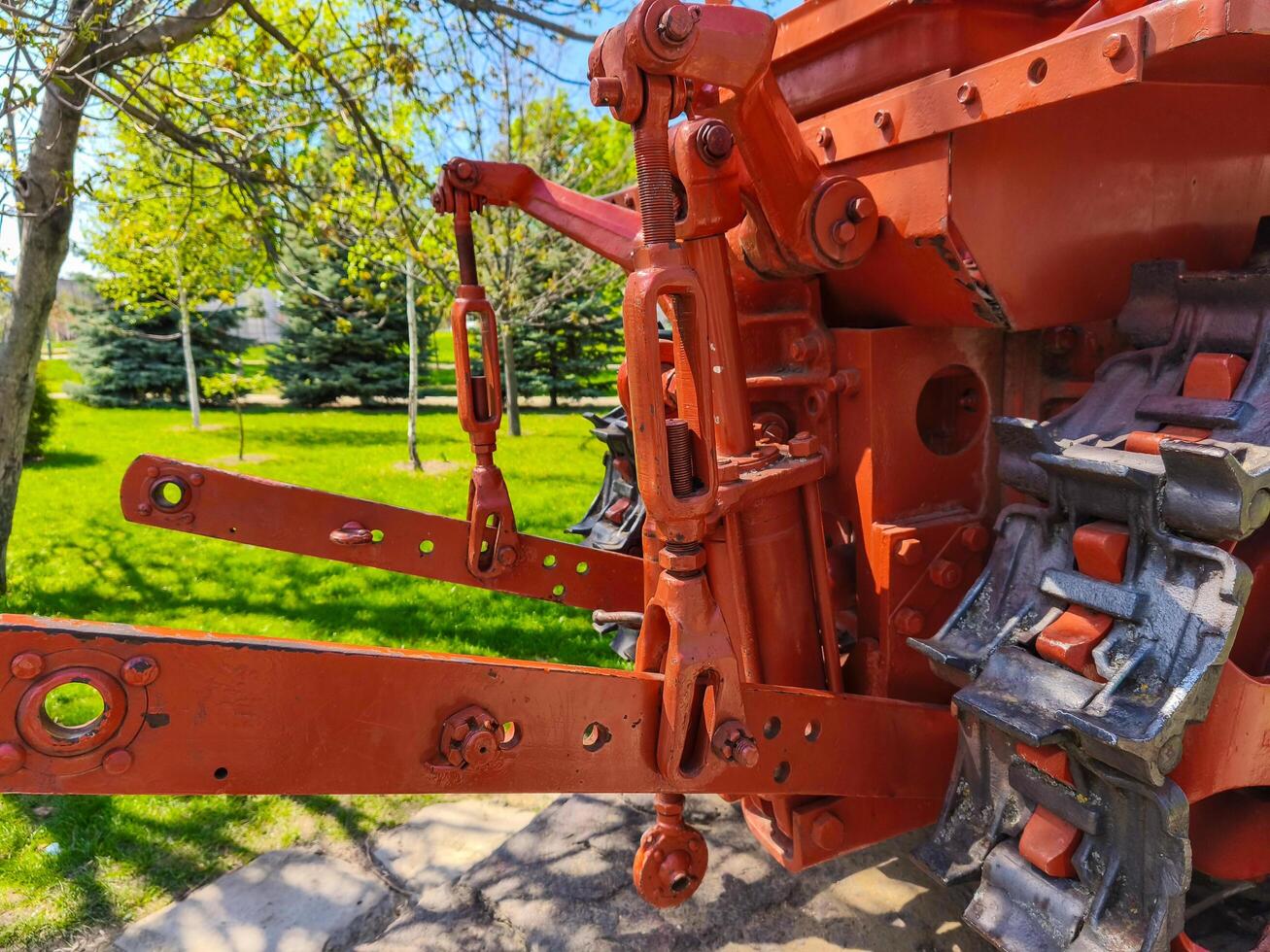 A red tractor with black wheels and a black frame. The tractor is parked in a grassy area photo