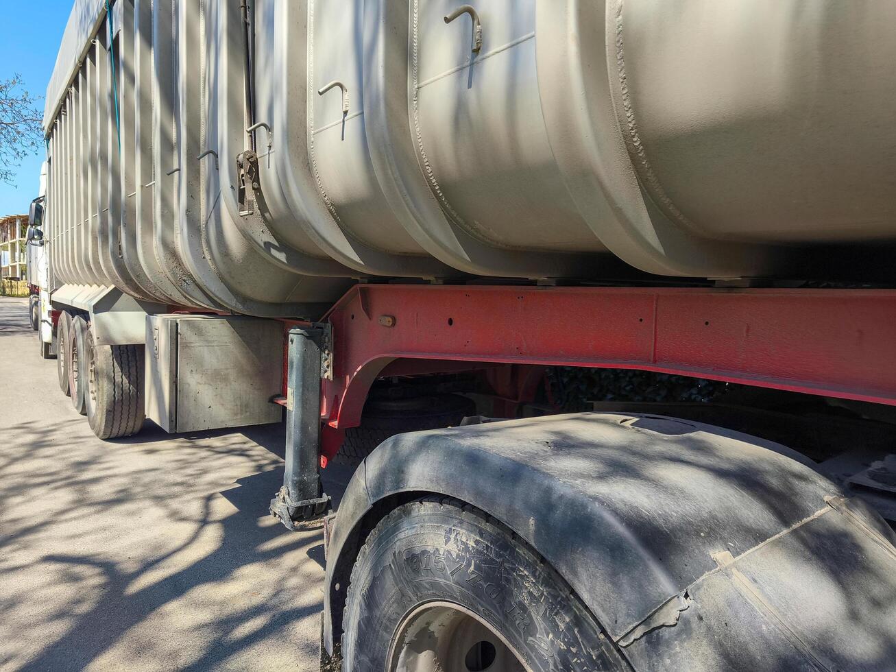 A semi truck with a red and black bumper. The truck is parked on a road photo