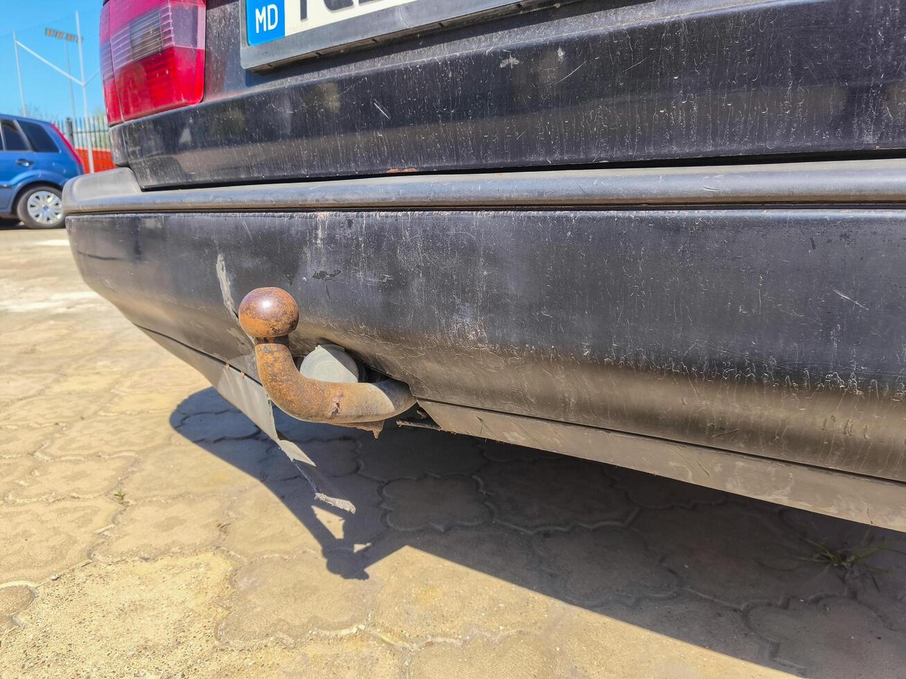 A black car with a rusty metal ball on the back. The ball is attached to a chain photo