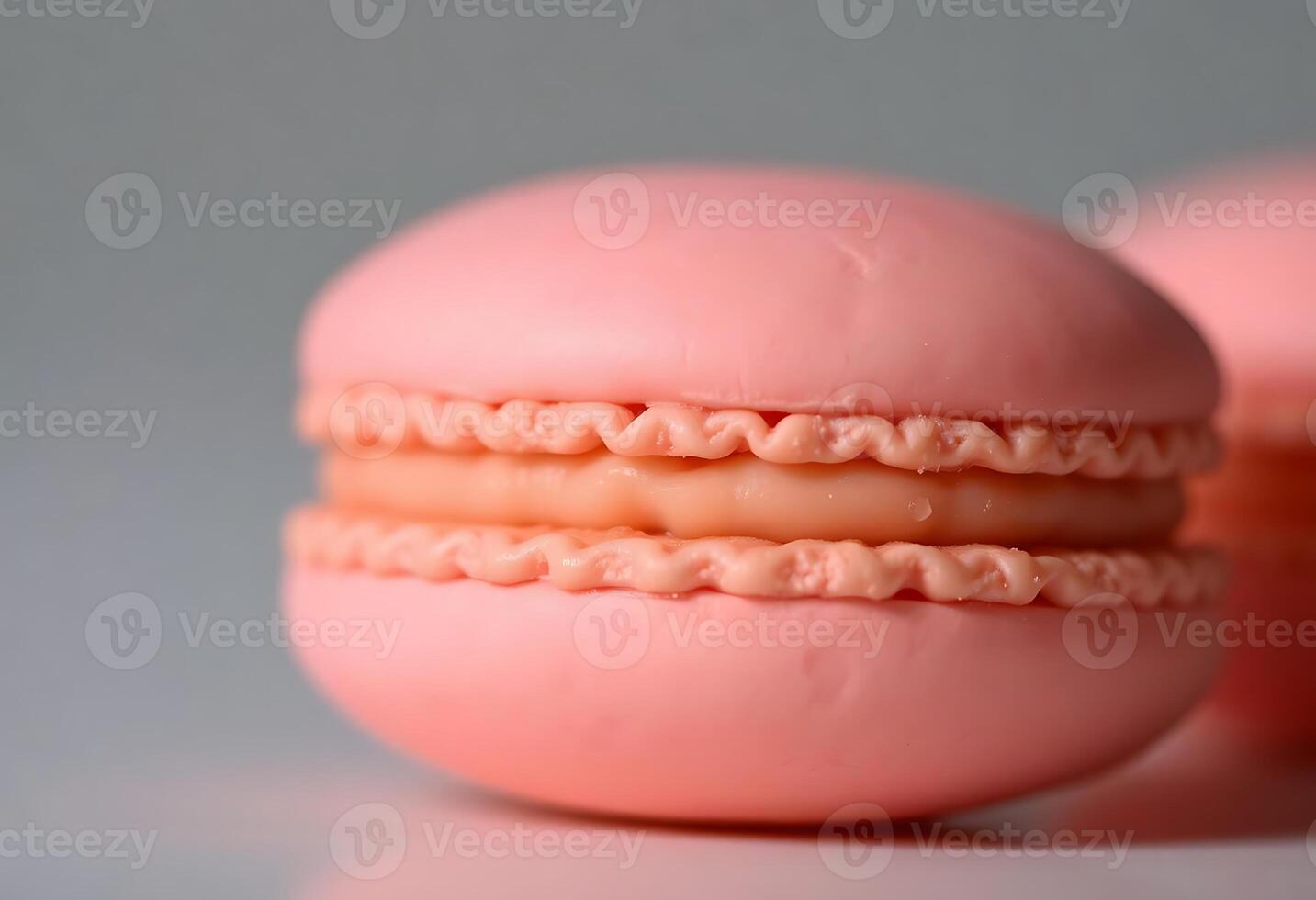 Two pink macarons are shown on a white surface photo