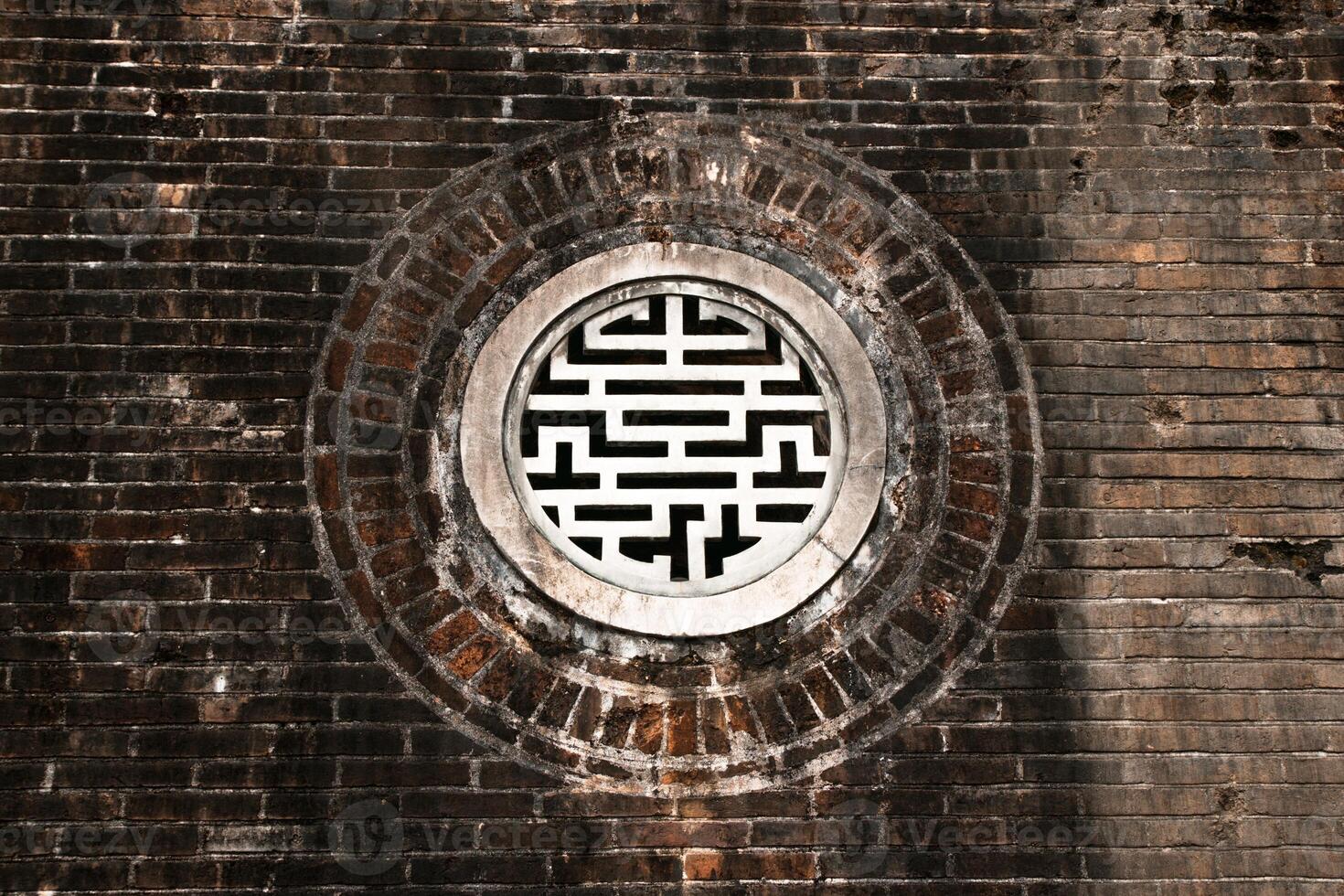 Beautifully Crafted Round Window Featuring Intricate Lattice Design Set in a Traditional Brick Wall. photo