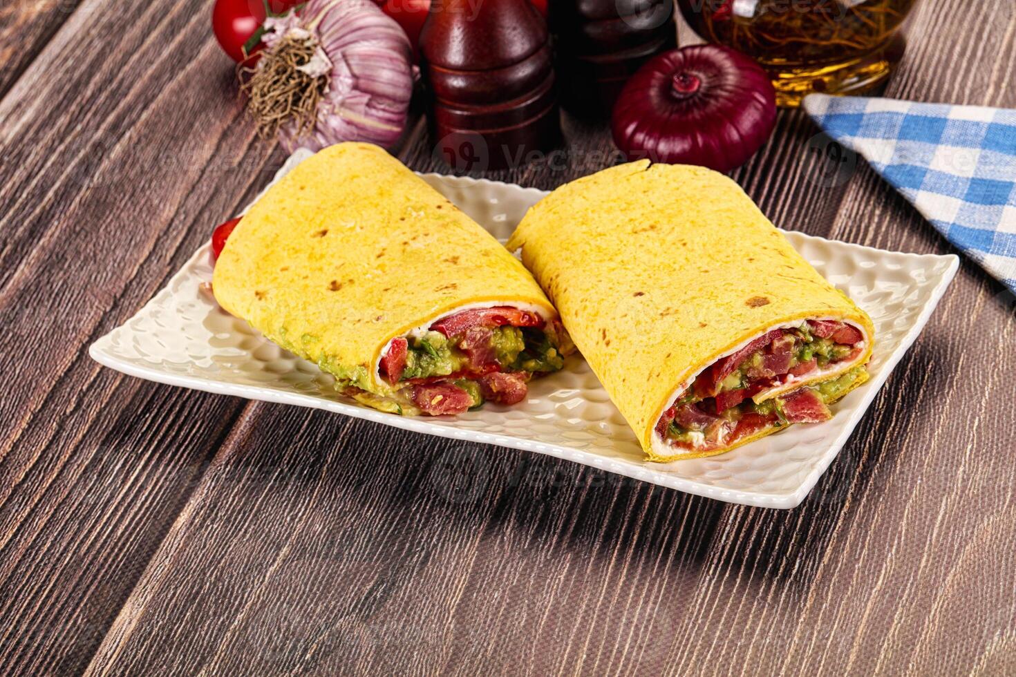 A plate with two burritos on it and some other ingredients photo