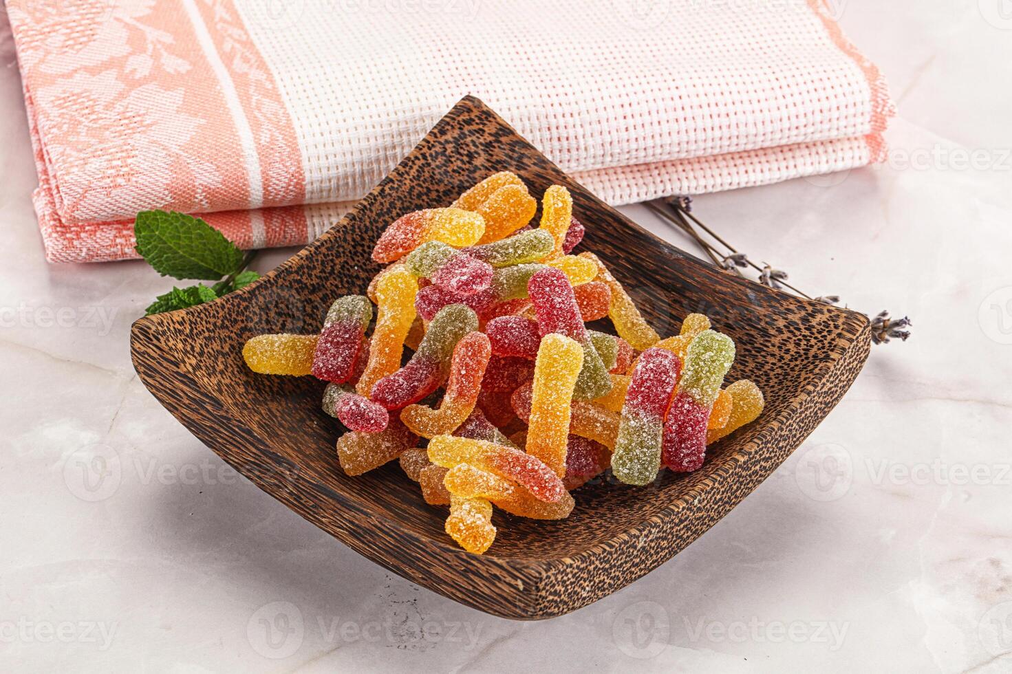 A wooden bowl filled with gummy worms photo
