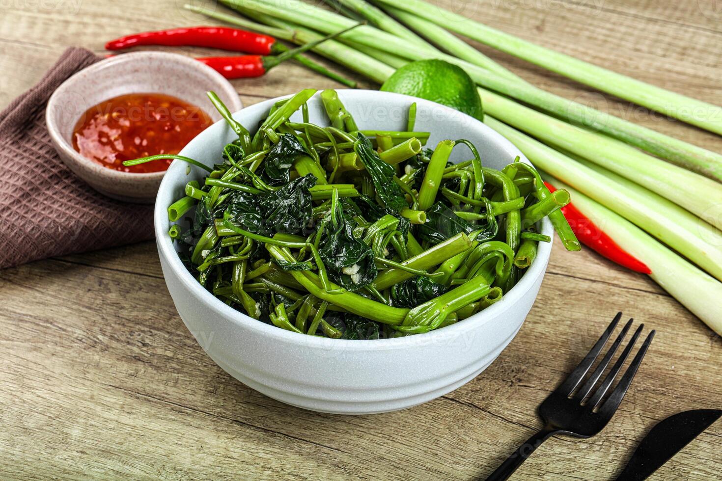 A bowl of green vegetables and a fork on a table photo