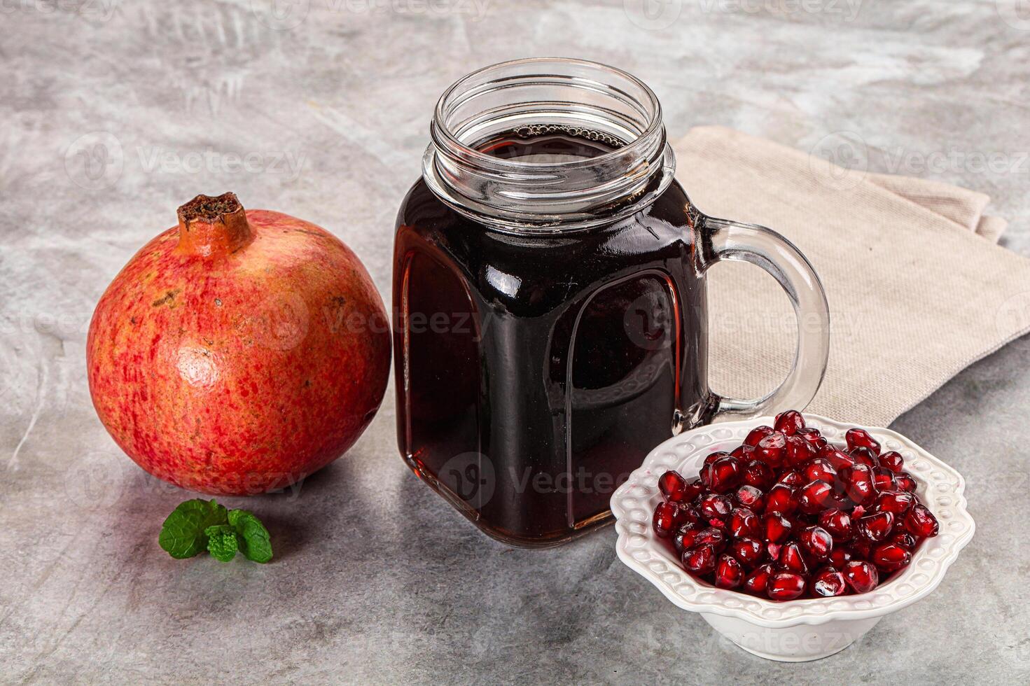 A glass jar with a pomegranate and a bowl of pomegranate photo