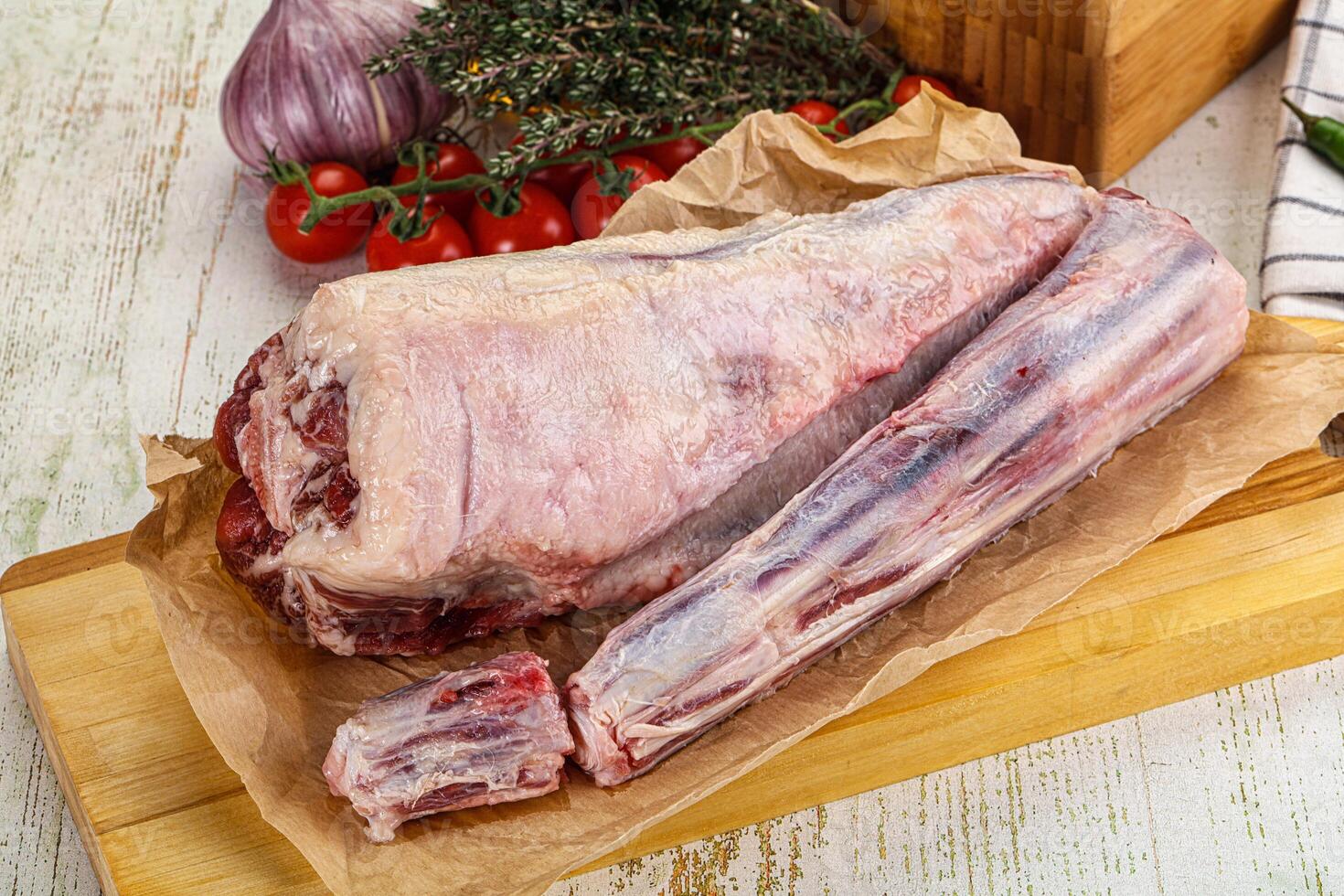 A raw lamb leg on a cutting board with a knife and a knife photo