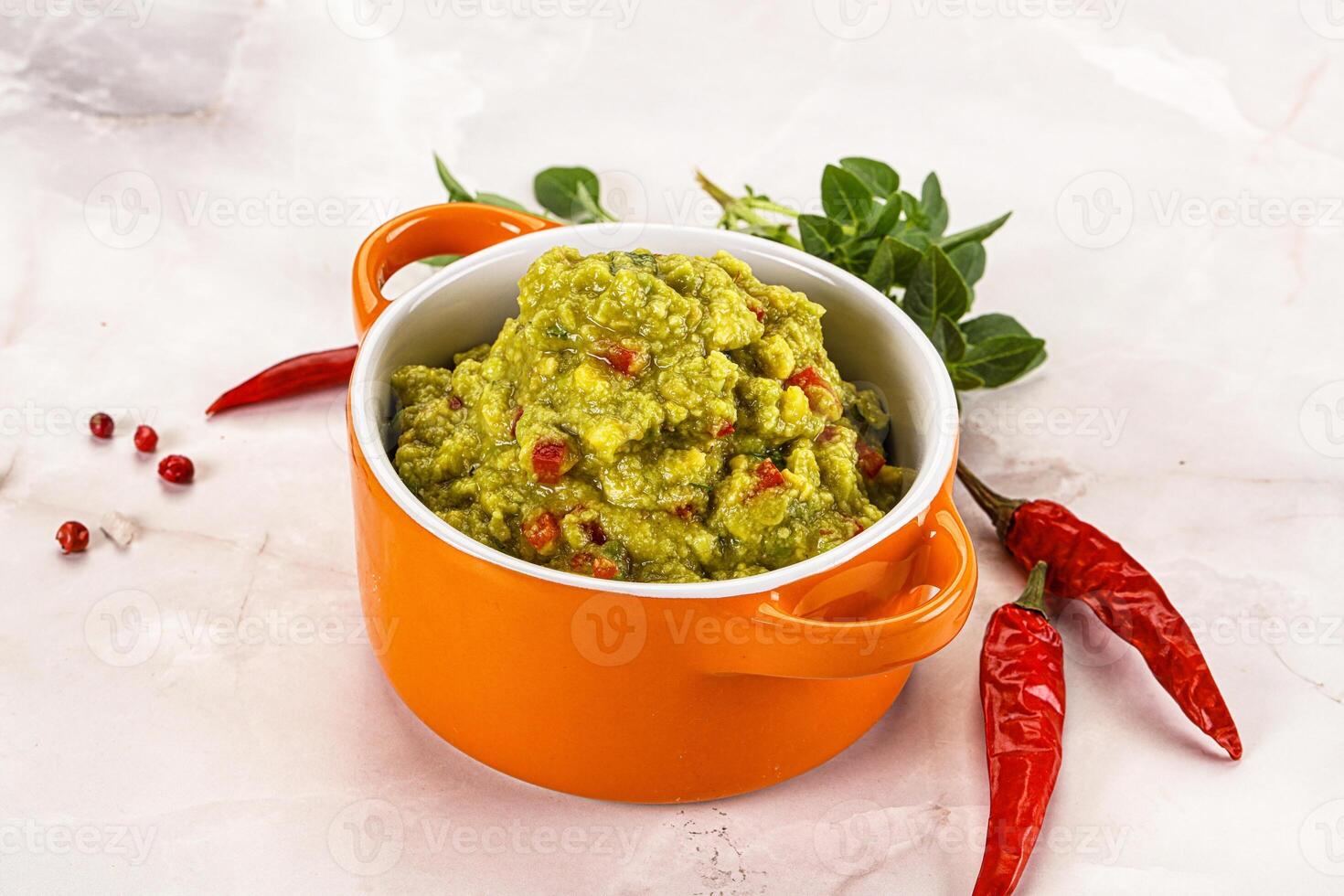 A bowl of guacamole with red peppers photo
