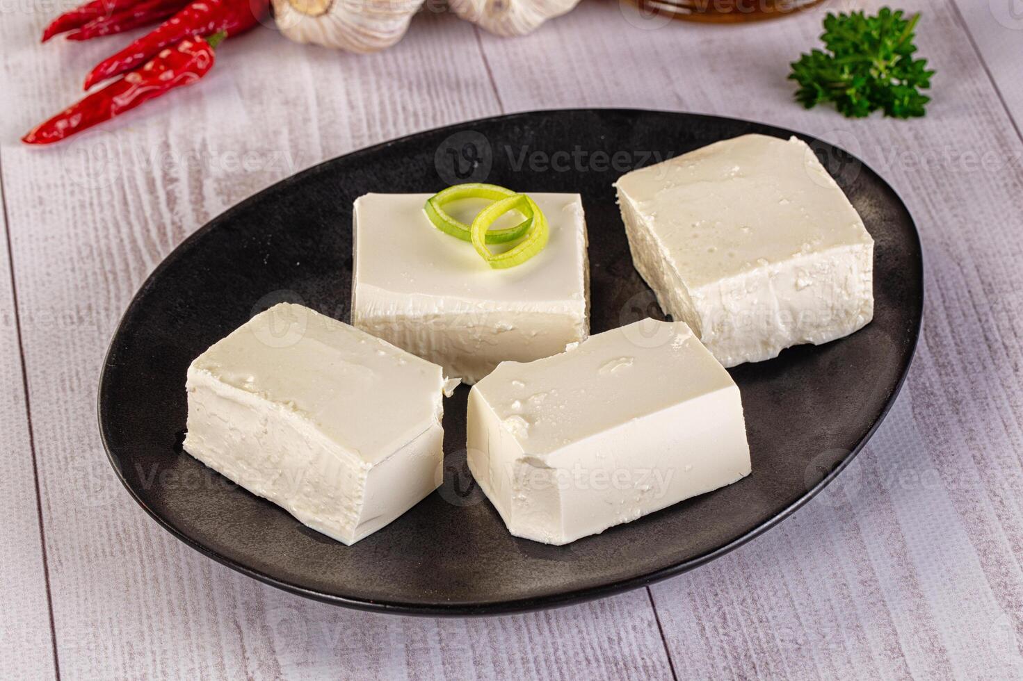 Four pieces of tofu on a black plate with garlic and other ingredients photo