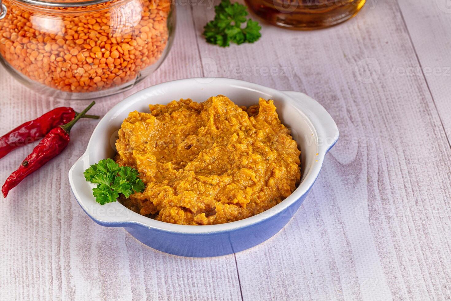 A bowl of lentil and a jar of chili peppers photo