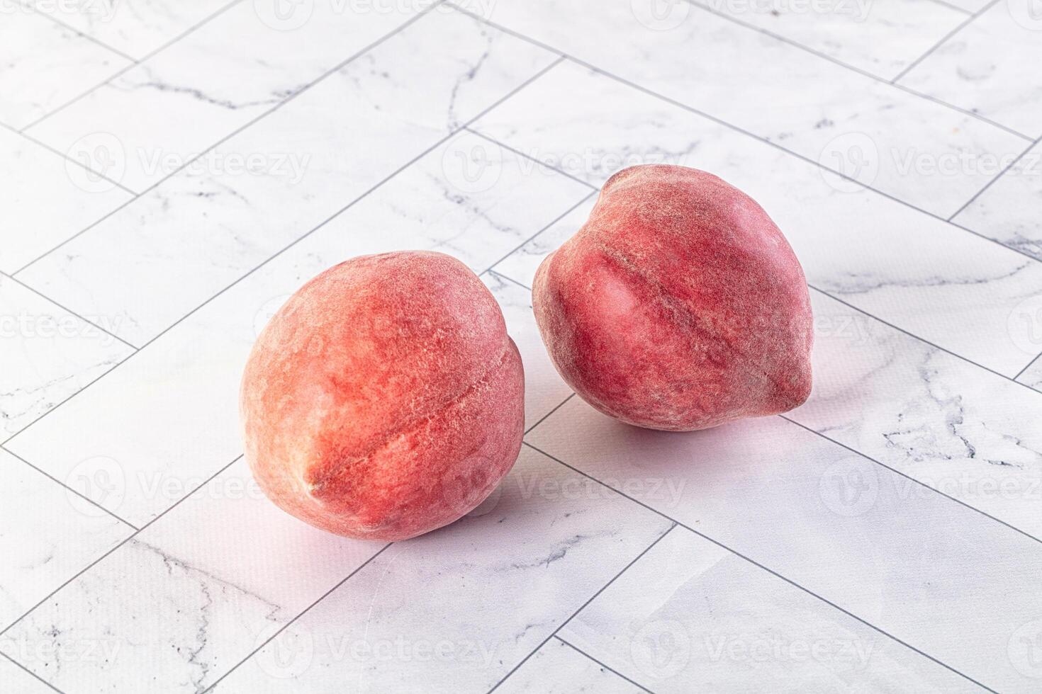 Two peaches on a white marble surface photo