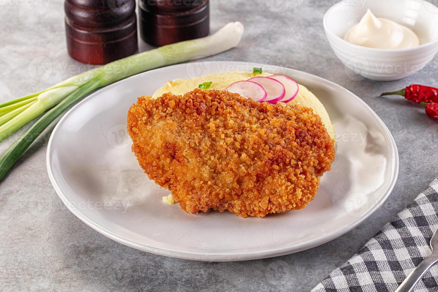 Fried chicken cutlet with mashed potatoes and pickles on a white plate photo