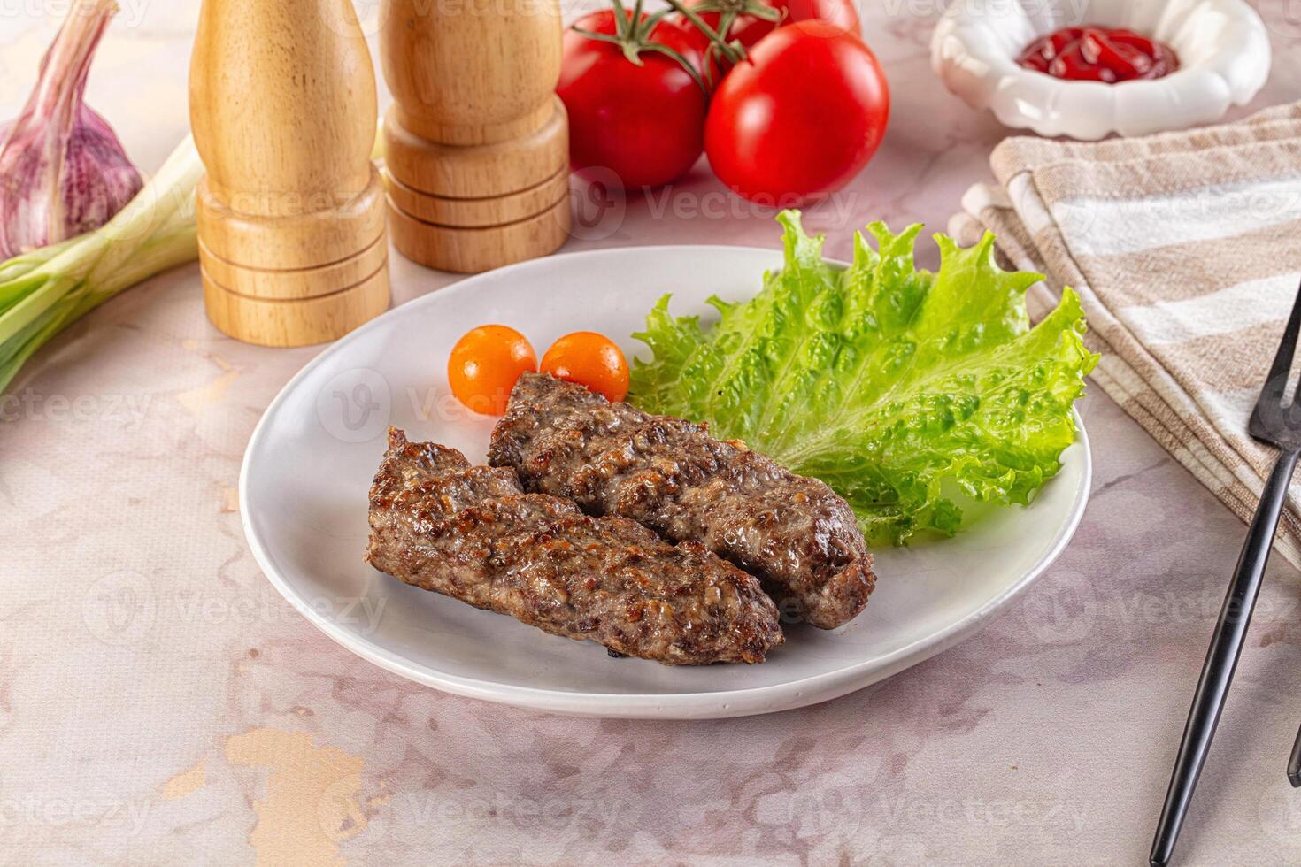 Two pieces of meat on a plate with vegetables and a knife photo