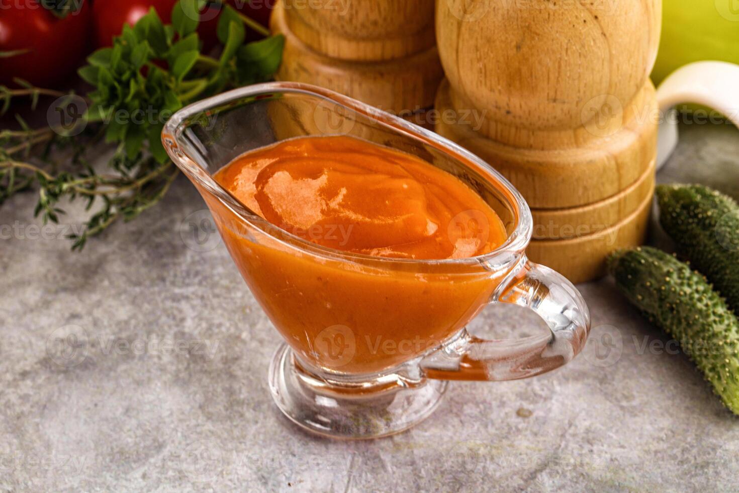 A glass pitcher filled with tomato sauce on a table photo