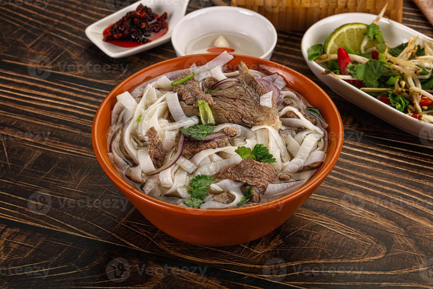 A bowl of noodles and a bowl of vegetables on a table photo