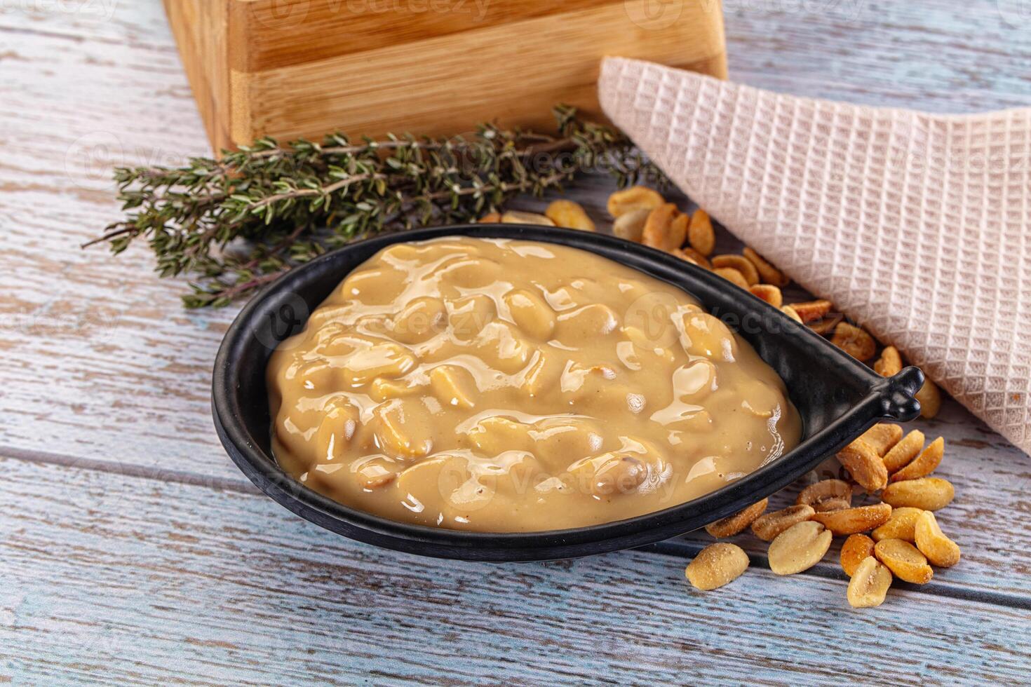 Peanut butter in a bowl with nuts and herbs photo