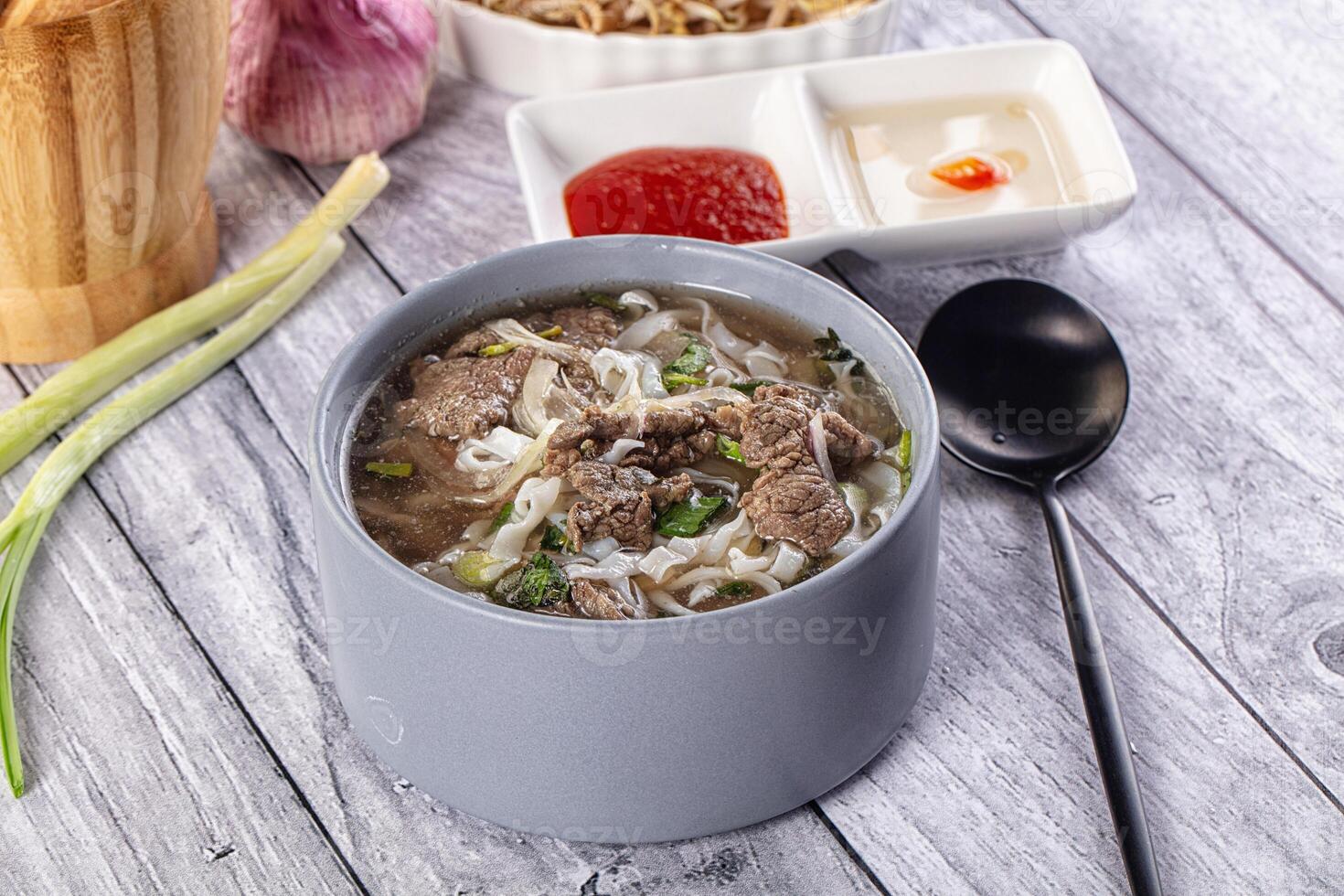 A bowl of soup with a spoon and chopsticks photo