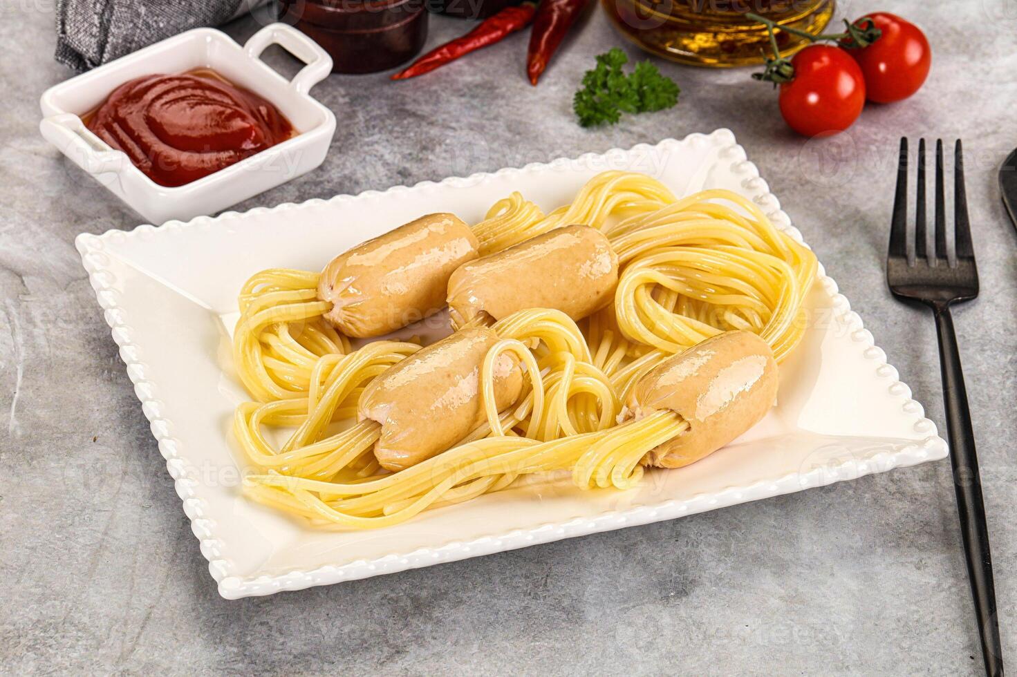 A plate of spaghetti and meatballs with ketchup and ketchup packets photo