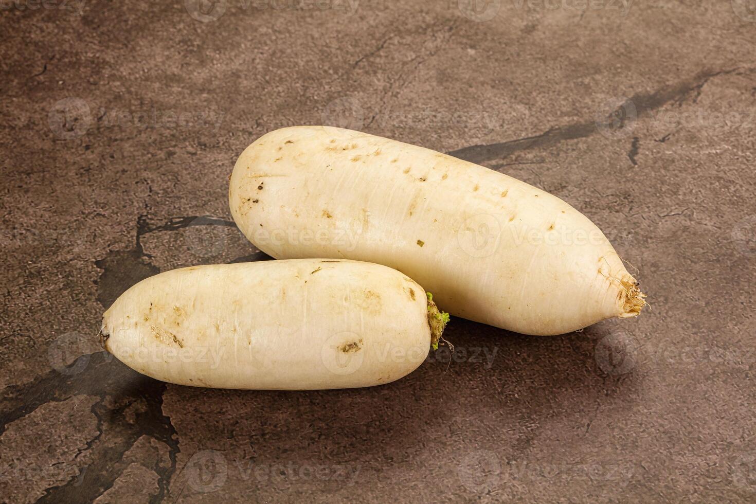 Two white radishes on a dark surface photo