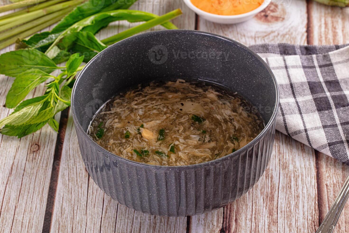 A bowl of soup with a spoon and some asparagus photo