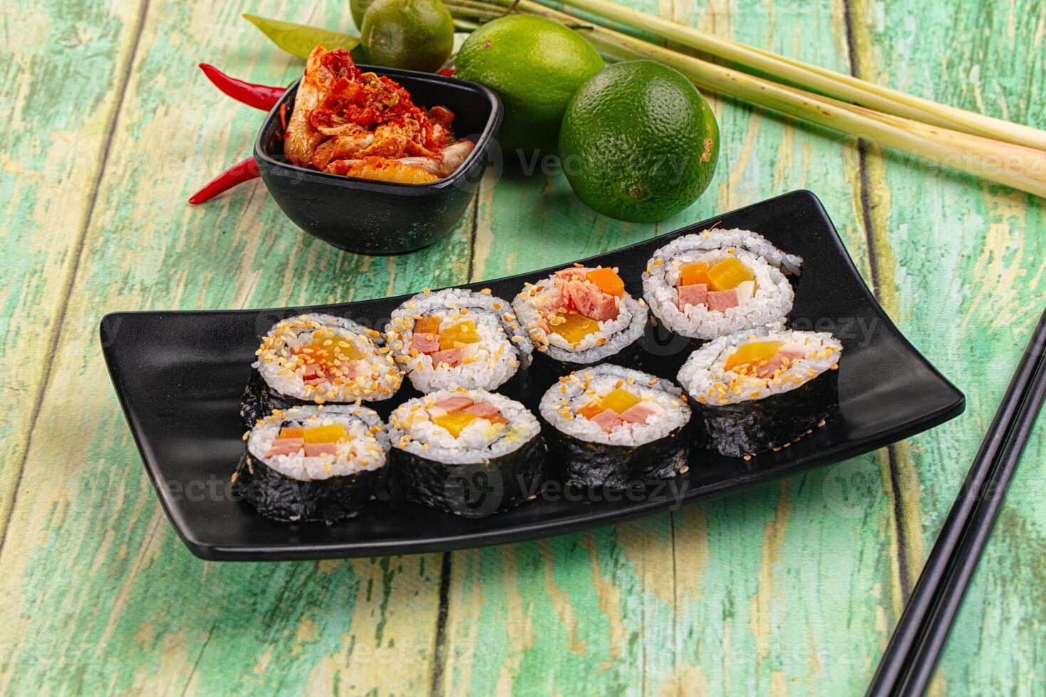 Sushi rolls with vegetables and chopsticks on a black plate photo