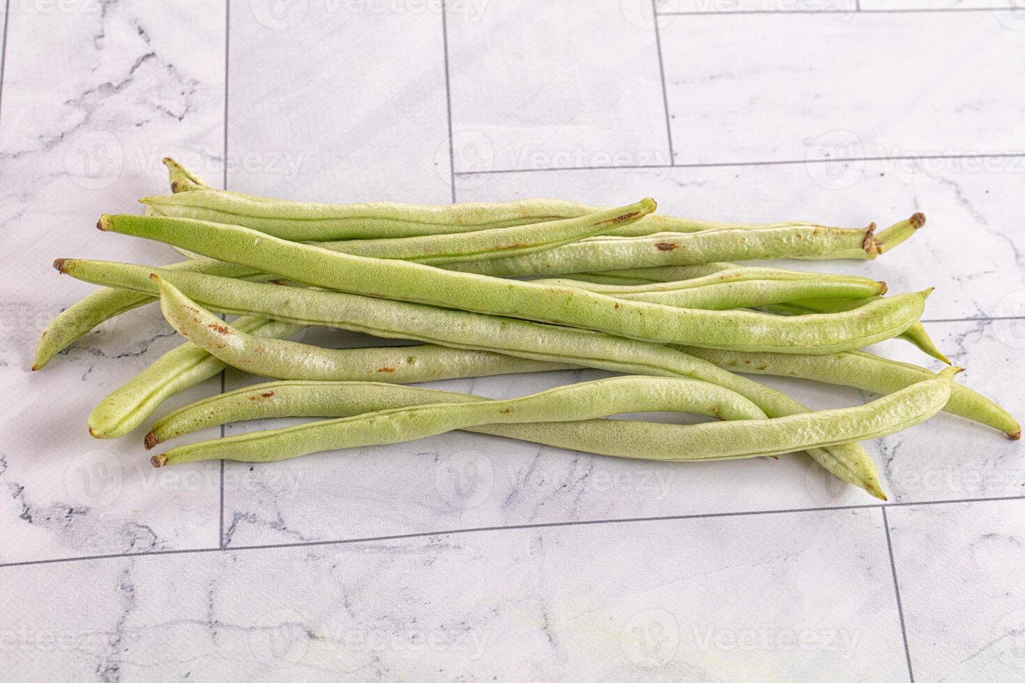 A pile of green beans on a marble counter photo