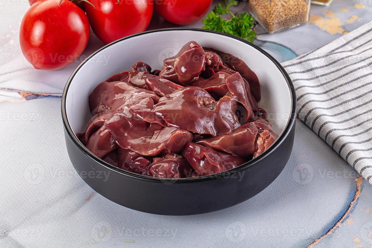 A bowl of raw meat sitting on a table next to tomatoes photo