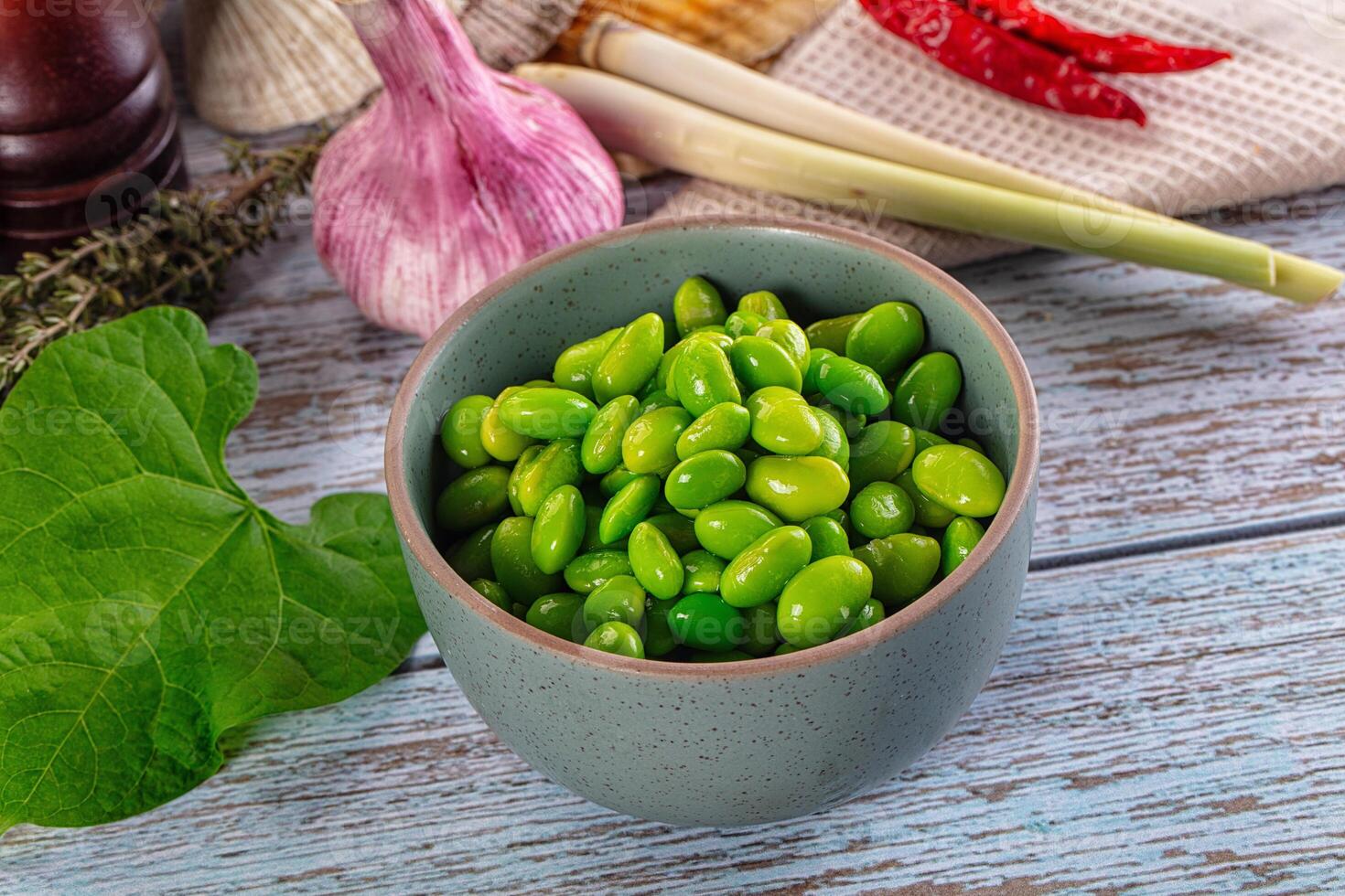 A bowl of green beans on a table next to other ingredients photo