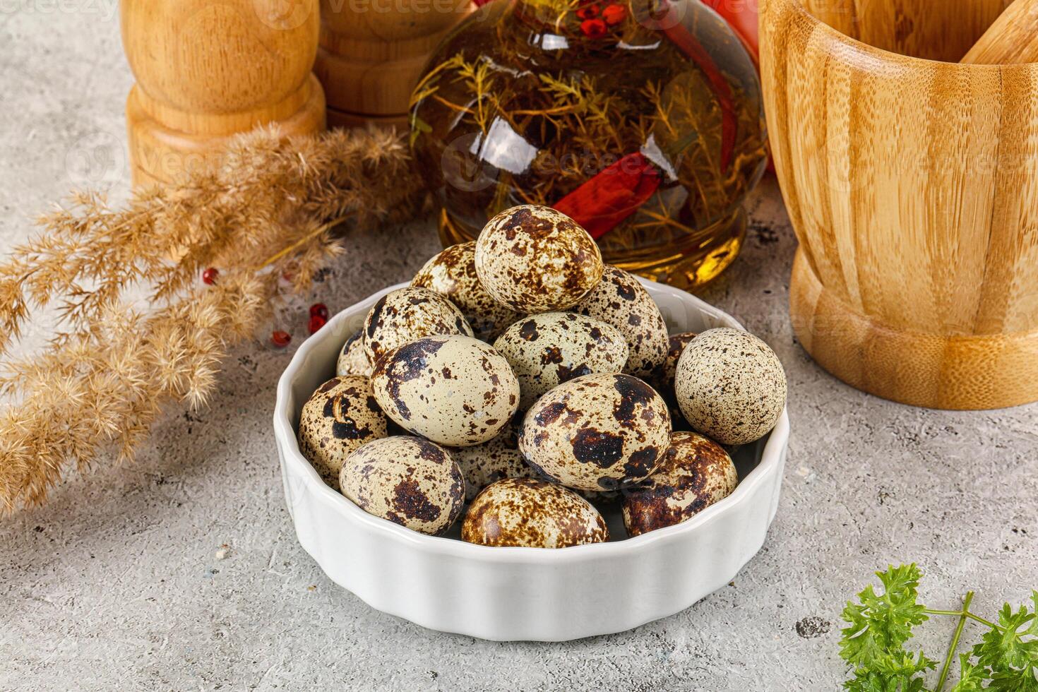 A bowl of quail eggs on a table next to a bowl of herbs photo