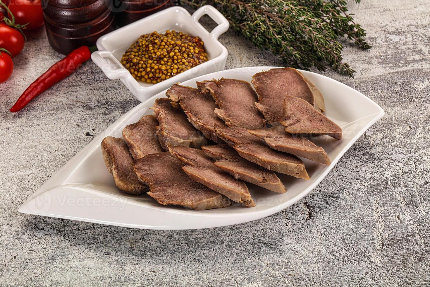 Sliced beef on a white plate with spices and other ingredients photo