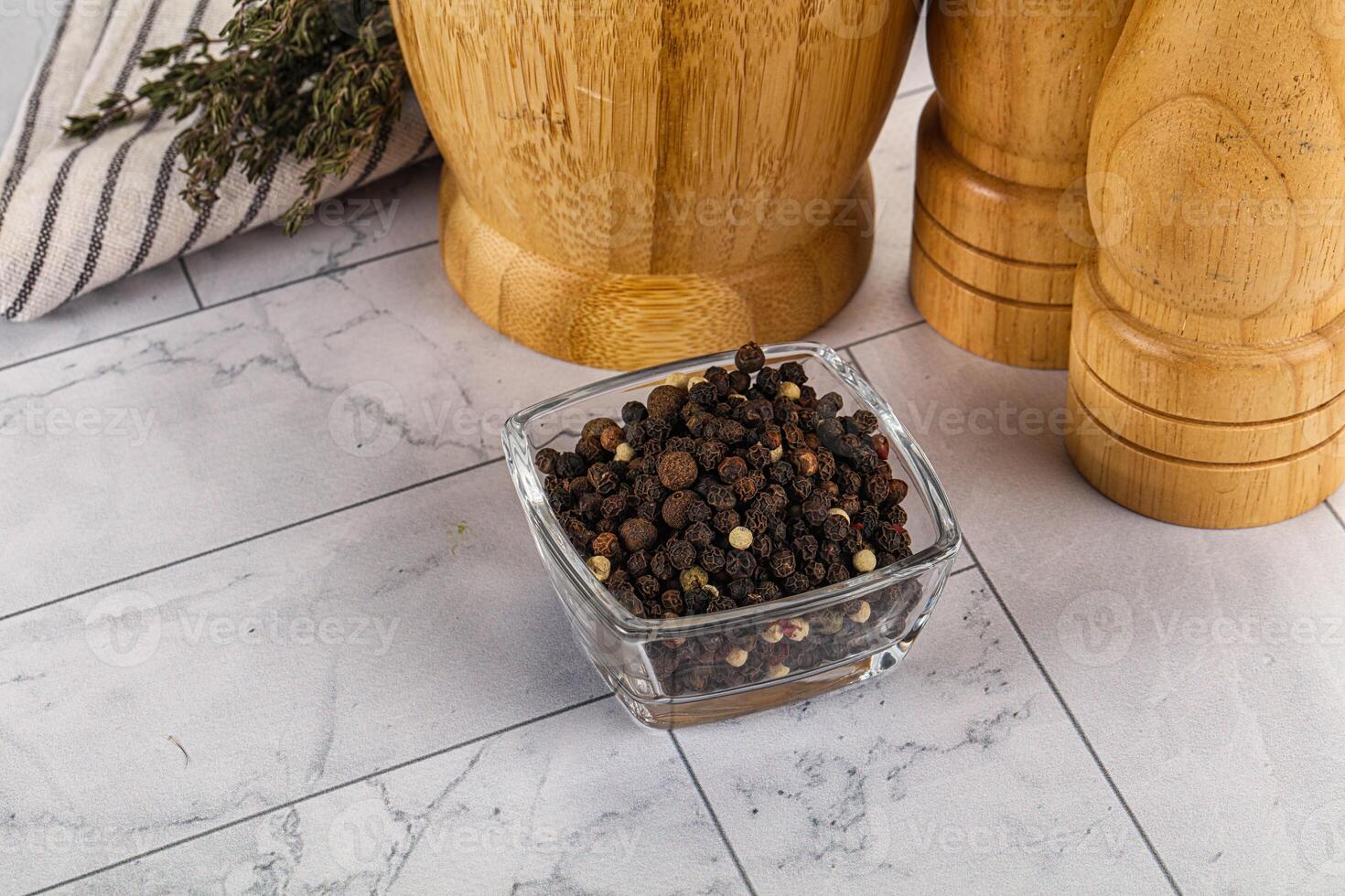 A glass container with pepper and spices on a marble counter photo