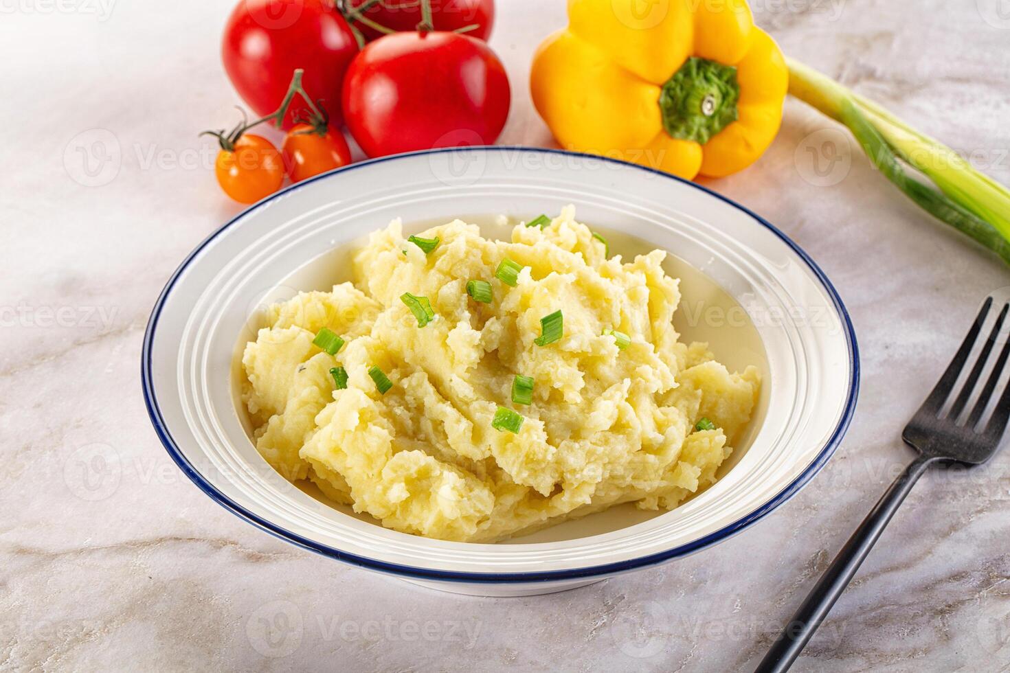 A bowl of mashed potatoes with vegetables on a marble counter photo