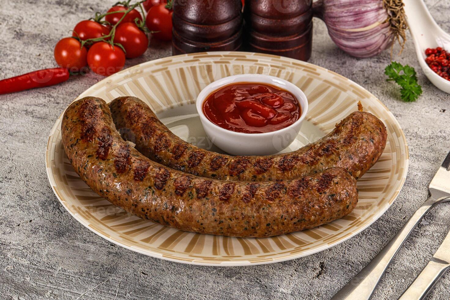 A plate with two sausages and a tomato sauce photo