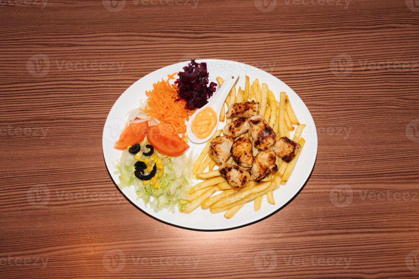 Turkish kebab plate with fries, vegetables and chicken. Delicious freshly prepared meal, perfect for menus, restaurants, or food delivery concepts. photo