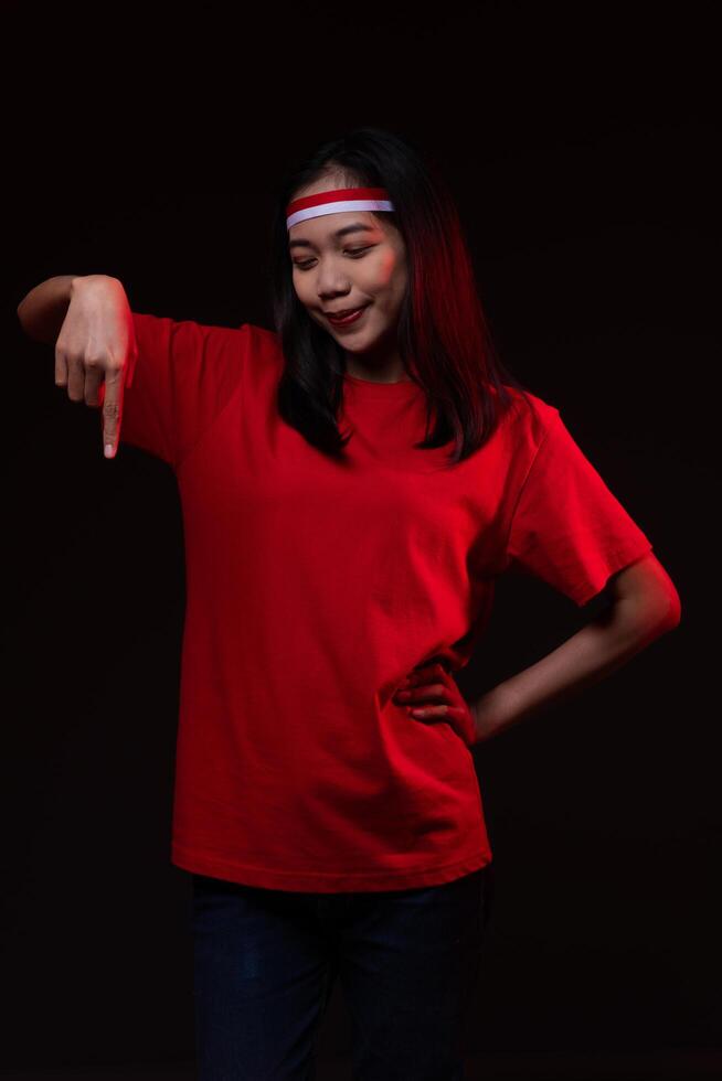 Portrait of Young Asian Woman Pointing Down Wearing Red Outfit, Indonesian Independence Day Concept Smiling Isolated photo