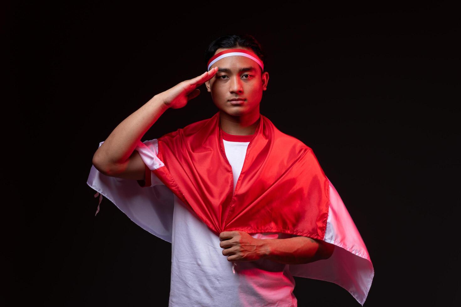 Portrait of Young Asian Man with Salute Gesture Wearing Red White Outfit, Indonesian Independence Day Concept Indonesian Flag photo