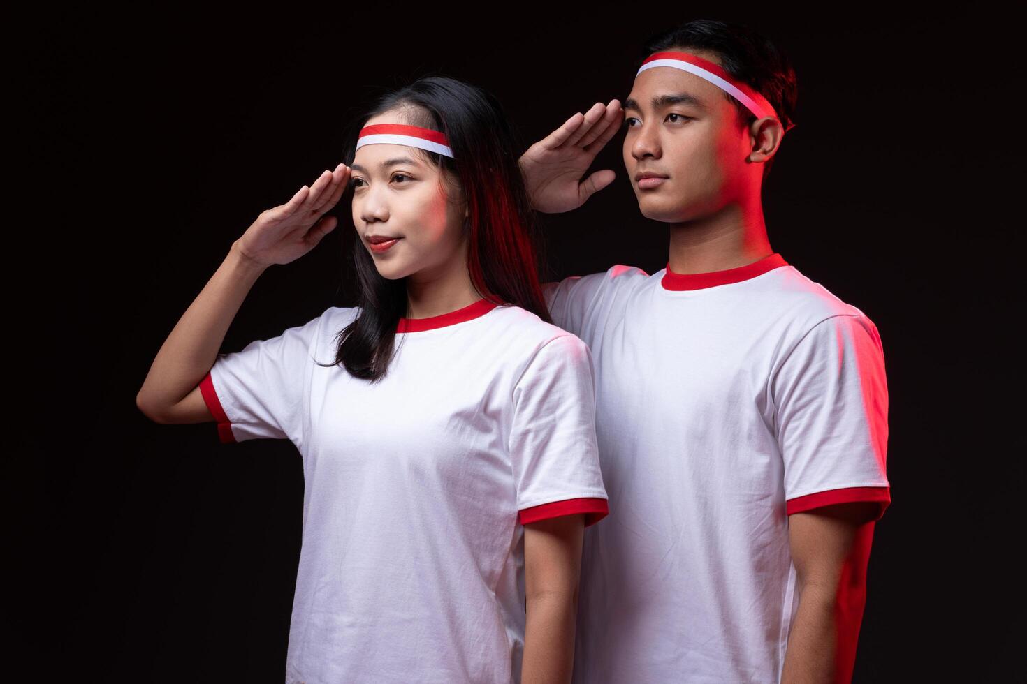 Portrait of Young Asian Man and Woman with Salute Gesture Wearing Red White Outfit, Indonesian Independence Day Concept photo
