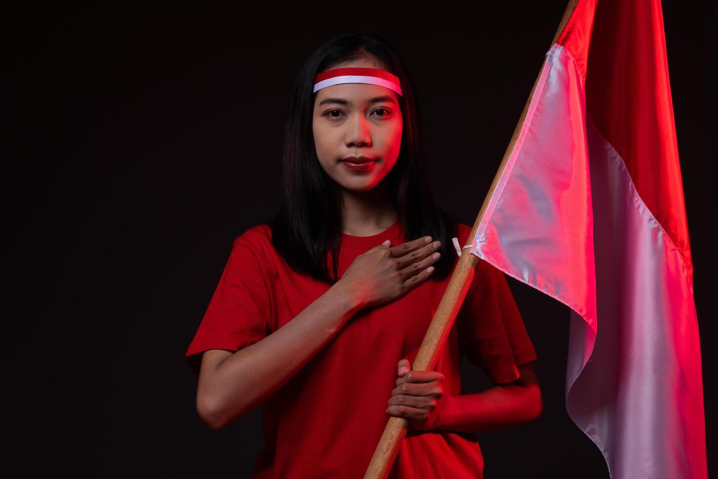 Portrait of Young Asian Woman with Salute Gesture Wearing Red Outfit, Indonesian Independence Day Concept Beautiful Smiling Isolated Background photo