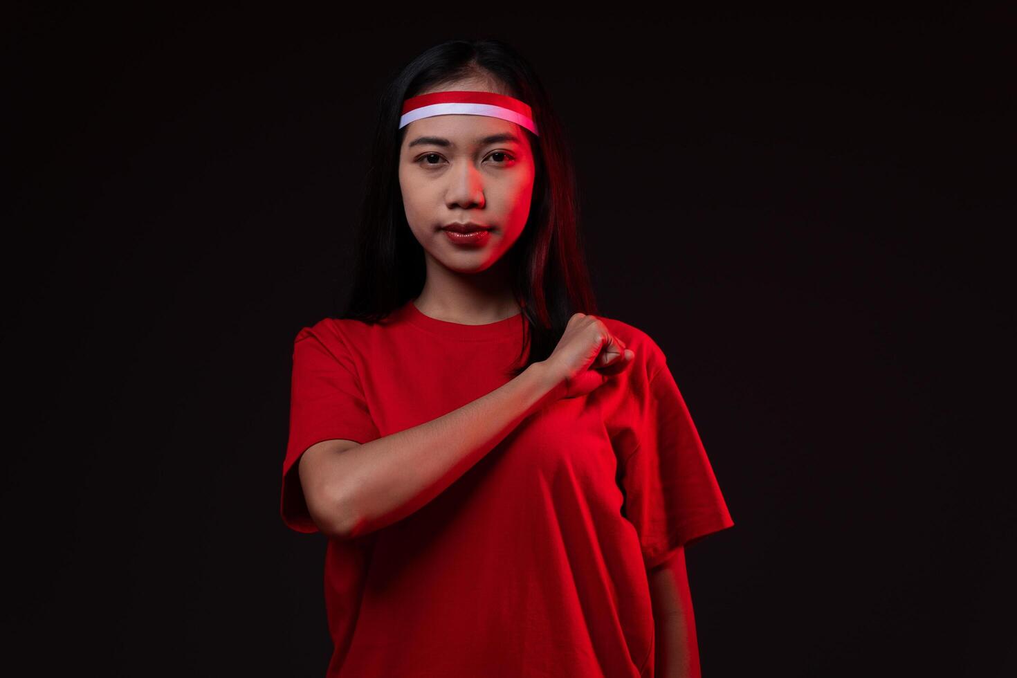 Portrait of Young Asian Woman with Salute Gesture Wearing Red Outfit, Indonesian Independence Day Concept Isolated photo