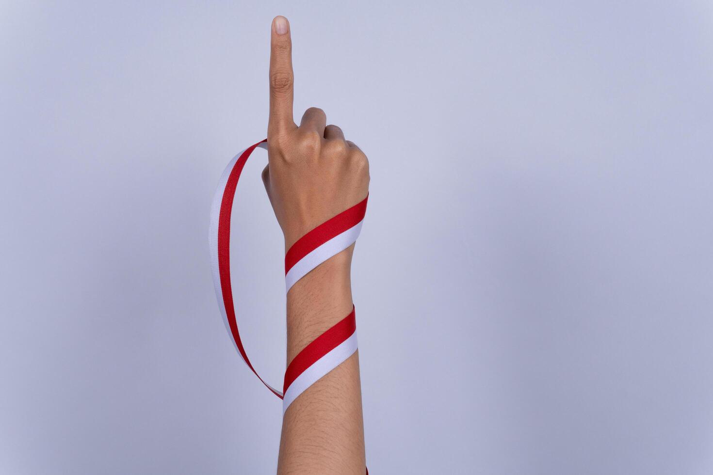 Hand Fist Holding a Red and White Ribbon, Indonesian Independence Day Concept Pointing Up photo